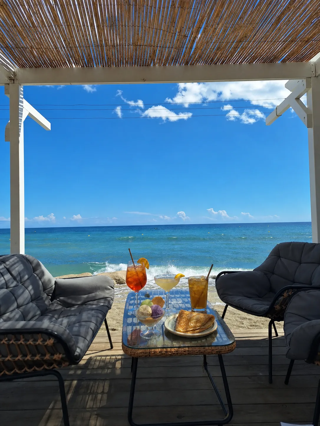 Table de terrasse face à la mer avec boissons et desserts
